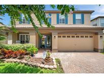 Charming two-story home showcasing a beautifully landscaped front yard and a welcoming brick-paved driveway at 1410 Halapa Way, Trinity, FL 34655