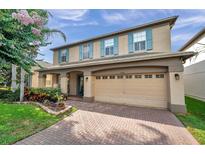 Charming two-story home featuring a brick driveway, blue shutters, and a well-maintained landscaped front yard at 1410 Halapa Way, Trinity, FL 34655