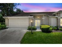 Charming single-story home with manicured lawn, neutral color palette, and attached two car garage at 1415 Pinewood Hills Ct, Spring Hill, FL 34606
