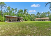 A house and large metal outbuilding are set on a large lot, surrounded by trees at 27295 Tarbel Rd, Brooksville, FL 34602