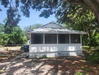 Charming cottage-style home featuring a screened-in front porch and mature trees providing ample shade at 3415 N 51St St, Tampa, FL 33619