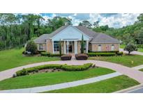 Beautiful brick home featuring a manicured lawn, elegant landscaping, and a circular driveway at 7275 Crystal Spring Run, Weeki Wachee, FL 34607