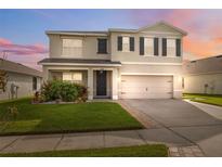 Charming two-story home boasts a well-manicured lawn and inviting covered porch, with a two-car garage and neutral paint at 8938 Bower Bass Cir, Wesley Chapel, FL 33545