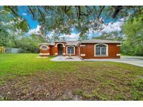 Charming single-story home featuring a well-manicured lawn, arched windows, and a welcoming front entry at 9130 Madrid Rd, Weeki Wachee, FL 34613