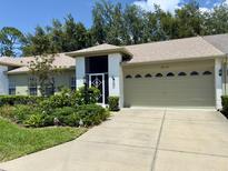 Charming single Gathering home showcasing lush landscaping and an attached two-car garage with a brick-paved driveway at 18142 Baywood Forest Dr, Hudson, FL 34667