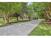 Long concrete driveway surrounded by lush greenery and mature trees leads to this single Gathering home at 11510 Lakeview Dr, New Port Richey, FL 34654