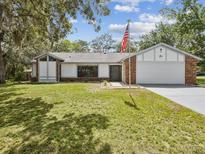 Charming single-story home with brick and white siding, an attached garage and a well-manicured front lawn at 2404 Knoll Dr, Spring Hill, FL 34608