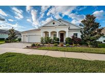 Charming single-story home featuring a manicured lawn, paver driveway, and an attached two-car garage at 4197 Glade Wood Loop, New Port Richey, FL 34655