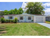 Charming single-story home with a well-manicured lawn, light blue accents, and attached two-car garage at 6144 Glenwood Dr, New Port Richey, FL 34653