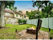 Inviting backyard featuring a fire pit and well-maintained lawn, perfect for outdoor relaxation and entertaining at 952 Coachlight Ln, Brooksville, FL 34601