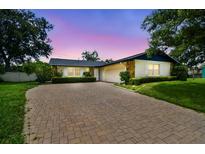 Charming home featuring a brick driveway, lush landscaping, and a well-maintained lawn at 1071 Lexington Ct, Largo, FL 33771