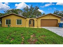 Cozy single-story home featuring a two-car garage, gated entrance, and bright yellow stucco at 2169 Danforth Rd, Spring Hill, FL 34608