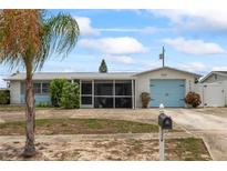 Charming single-story home featuring a screened-in porch and a delightful light blue garage door at 5321 Mosaic Dr, Holiday, FL 34690