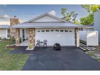 Charming home featuring stone accents, a metal roof, and a freshly paved driveway leading to an attached two-car garage at 5520 Fulmar Dr, Tampa, FL 33625