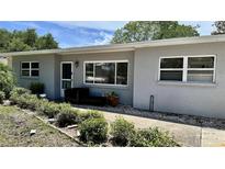 Inviting single-story home with neutral gray exterior, well-maintained landscaping, and cozy front seating area at 723 W Bayshore Dr, Tarpon Springs, FL 34689