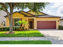 Charming single-story home featuring a well-manicured lawn, mature tree, and a two-car garage at 758 Alpine Thistle Dr, Brooksville, FL 34604