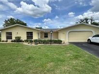Charming single-story home featuring an attached two-car garage and lush green lawn at 12104 Boynton Ln, New Port Richey, FL 34654