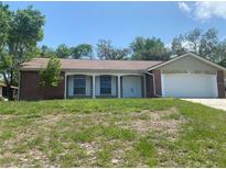 Charming single story home featuring a brick facade, 2-car garage and a well-manicured lawn at 1392 Piper Rd, Spring Hill, FL 34606