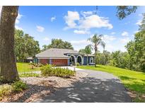 Beautiful single-story home with a lush lawn, mature landscaping, and a long driveway leading to the three-car garage at 22850 Skyview Cir, Brooksville, FL 34602