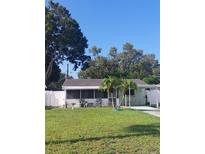 Charming home featuring a white picket fence, screened-in porch, and lush green lawn with young palm trees at 2870 26Th N Ave, St Petersburg, FL 33713
