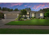 Charming single-story home featuring a lush front lawn, mature landscaping, and welcoming double-door entry under a twilight sky at 5072 Abbonmarsh Cir, Brooksville, FL 34604