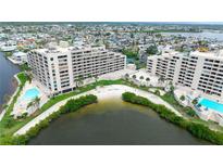 Stunning aerial view of condo community featuring lush landscaping, private beach, and inviting swimming pools at 6035 Sea Ranch Dr # 410, Hudson, FL 34667