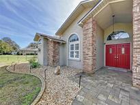 Inviting front entrance featuring a vibrant red double door, brick accents, and lush landscaping at 10060 Chip Ln, New Port Richey, FL 34654