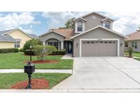 Charming home with a two-car garage, beautiful landscaping, and a well-manicured lawn on a sunny day at 11418 Tee Time Cir, New Port Richey, FL 34654
