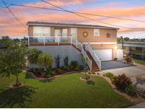 Charming raised bungalow with manicured lawn, lovely landscaping, and a covered front porch at 13027 Beacon Ct, Hudson, FL 34667