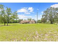 Sprawling single-story home with lush front lawn and mature trees on a sunny day at 13180 Montour St, Brooksville, FL 34613