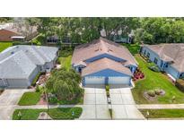 Charming blue home with a two-car garage, landscaped front yard, and mature landscaping at 13321 Norman Cir, Hudson, FL 34669