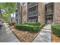 Multi-story brick building with landscaped walkway, bushes, and trees in a well-maintained community at 2500 Winding Creek Blvd # G106, Clearwater, FL 33761