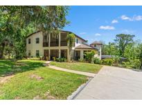 Charming two-story home featuring screened porches, a turret, beautiful landscaping, and a concrete driveway at 25487 Dan Brown Hill Rd, Brooksville, FL 34602
