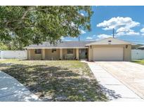 Charming single-story home with a brick facade, well-maintained lawn, and attached two-car garage at 2954 Leisure Ct, Dunedin, FL 34698