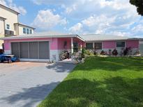 Charming pink home with a well-maintained lawn and brick-paved driveway, creating a welcoming curb appeal at 3336 Gulfview Dr, Hernando Beach, FL 34607