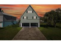 A-frame stilt home with green siding, black shutters, and covered parking area at ground level at 3363 Poinsettia Dr, Hernando Beach, FL 34607