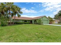 Charming single-story home with green exterior, lush lawn, and mature palm trees at 5021 Bridgeport Dr, Safety Harbor, FL 34695