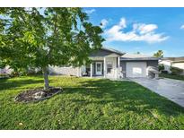 Charming single-story home with a well-manicured lawn and a tree in the front yard at 7118 Cherry Laurel Dr, Port Richey, FL 34668