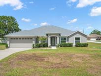 Charming single-story home with a well-maintained lawn and a two-car garage and decorative shrubs along the front of the house at 8199 Nordica Rd, Weeki Wachee, FL 34613