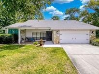 Charming single-story home with stone accents, a well-manicured lawn, and an attached two-car garage at 8979 Hernando Way, Weeki Wachee, FL 34613