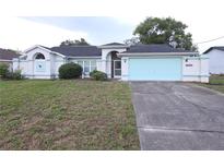 Charming single-story home features a light blue garage door and nicely landscaped yard at 11263 Murraysville Dr, Spring Hill, FL 34609