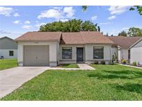 Charming single-story home with manicured lawn, inviting entryway, and attached one car garage at 11725 Spring Tree Ln, Port Richey, FL 34668