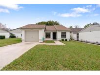 Charming single-story home featuring a well-manicured lawn and attached one car garage at 11725 Spring Tree Ln, Port Richey, FL 34668
