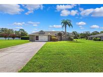 Charming single-story home with a well-manicured lawn and a palm tree in the front yard at 1478 Brigadier Dr, Spring Hill, FL 34608