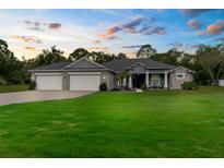 Charming single Gathering home featuring a well-manicured lawn, 3-car garage and inviting front porch at 2111 Maximilian Ave, Spring Hill, FL 34609
