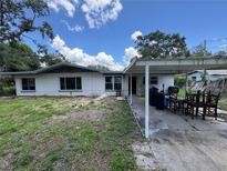 Modest single story home with white siding, a carport, and a lawn needing maintenance at 34767 Evergreen Way, Ridge Manor, FL 33523