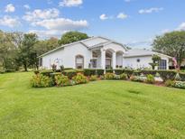 Charming single-story home featuring lush landscaping with flower beds at 489 Tournament Dr, Spring Hill, FL 34608