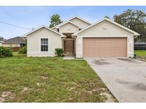 Charming single-story home featuring a neutral color scheme, attached garage, and well-manicured lawn at 5048 Teather St, Spring Hill, FL 34608