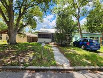 Quaint single-story home featuring a screened front porch and mature trees at 5748 Montana Ave, New Port Richey, FL 34652