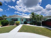 Charming single-story home with a well-manicured lawn and tropical landscaping, enhanced by bright blue skies and fluffy clouds at 6737 Clark St, Hudson, FL 34667